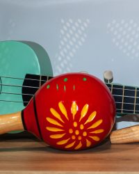 Red maracas and green small Ukulele guitar on wooden shelf. Mexican traditional musical instruments set in music store