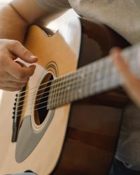 Man plays an acoustic guitar in a room at home. Hobby a musician. life at home